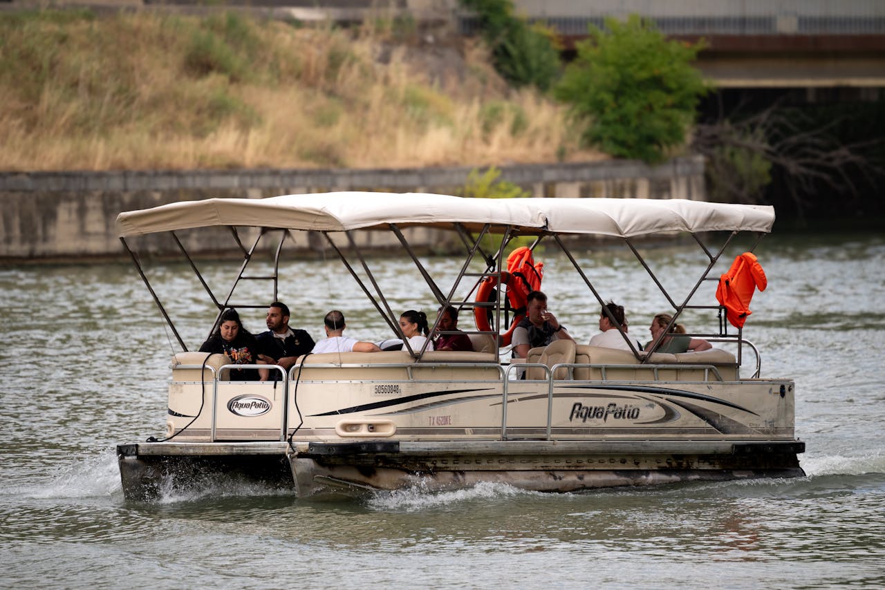 services-05 Pontoon boat cruising on a river with diverse passengers enjoying a sunny day in Tbilisi.