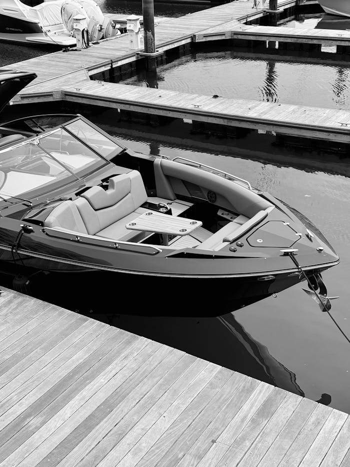services-06 Black and white photo of a modern boat docked at a marina, showcasing sleek design.