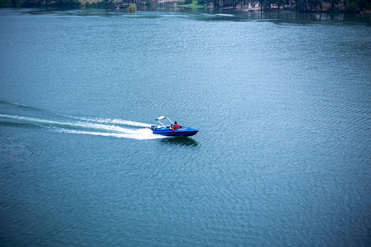 about-us Aerial view of a blue speedboat creating waves on a vast lake under clear skies.